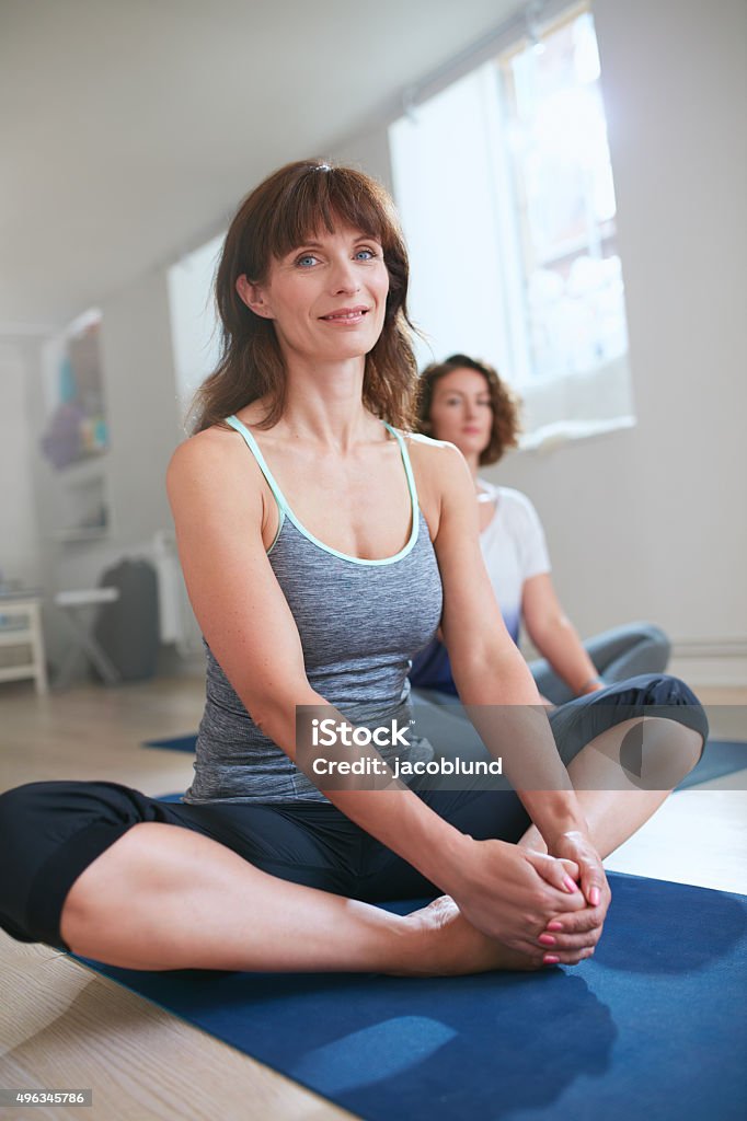 Fitness trainer in Baddha konasana yoga pose Portrait of female fitness trainer sitting on floor in Baddha konasana yoga pose. Women in yoga class sitting in butterfly pose. 2015 Stock Photo