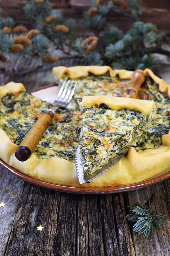 New Year mood: spinach quiche and pine branches on wooden table