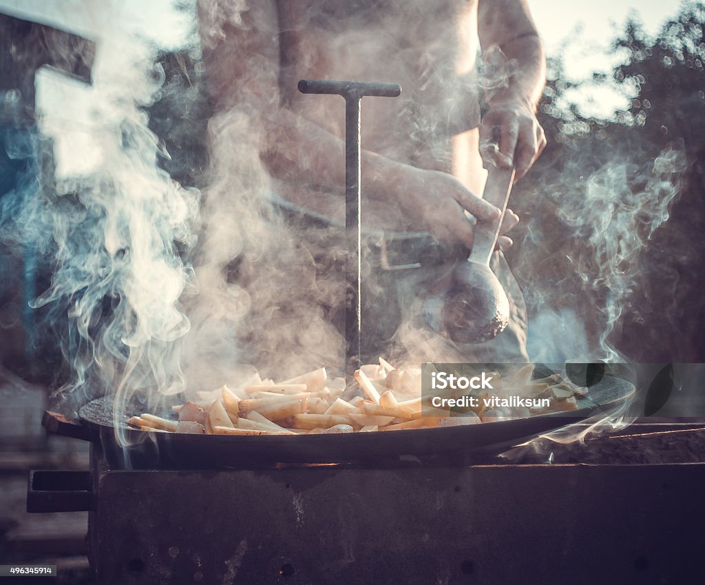 man preparing a meal man preparing a meal on a fire. 2015 Stock Photo