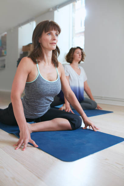 istock Women at yoga class practicing pigeon pose 496346036