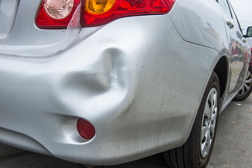 A car has a dented rear bumper after an accident