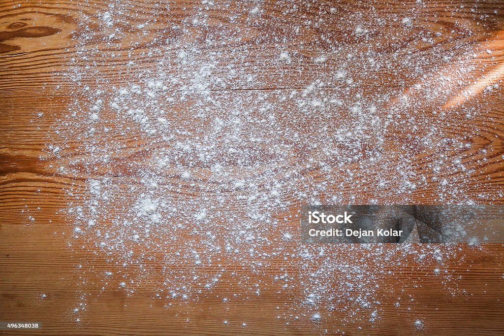 White flour scattered on rustic wooden board, Baking background White flour scattered on rustic wooden board with ray of sunlight coming from side. Baking background. Powdered Sugar Stock Photo