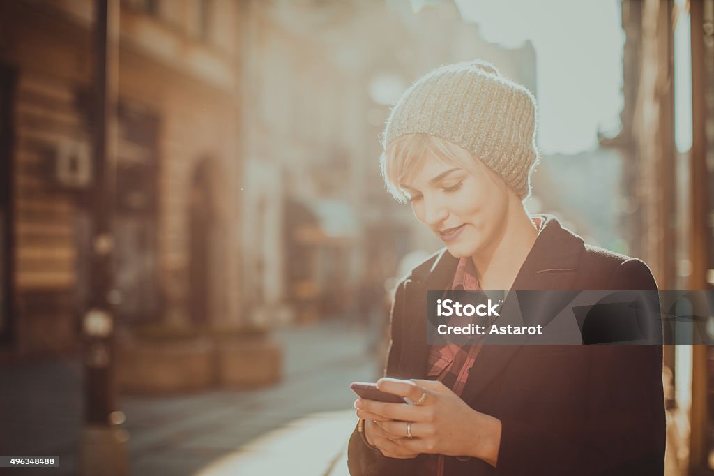 Young woman using her mobile phone Beautiful young woman standing at the street and using her mobile phone Mobile Phone Stock Photo