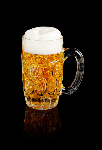 Beer stein with foamy beer isolated on black.