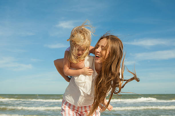 istock Mother and daughter having fun playing on the beach 496350256