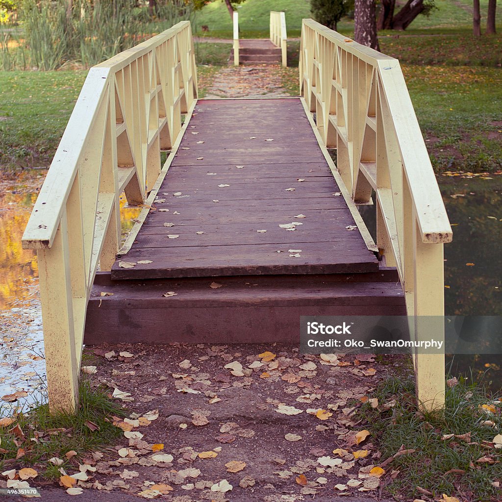 Wooden bridge on lake at park Wooden bridge on lake or river at park or outdoors, with autumn leaves. 2015 Stock Photo