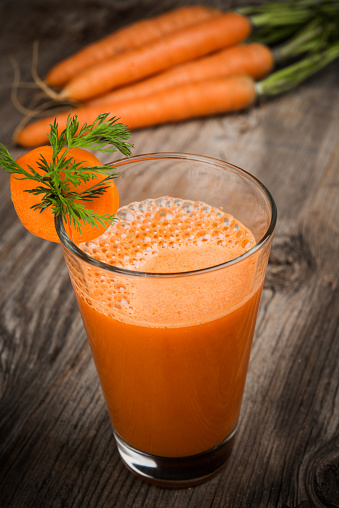 Fresh made carrot juice with decoration on vintage wooden background