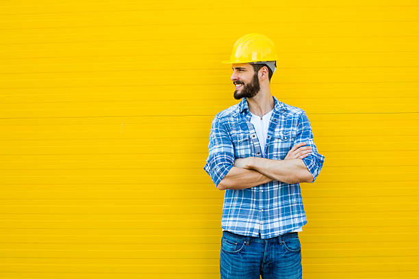 adult worker with helmet on yellow wall stock photo