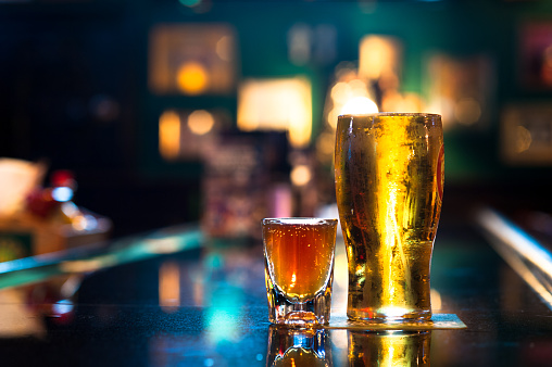 Pint of Ale Beer and shot of Whiskey on Bar with colorful lights in background