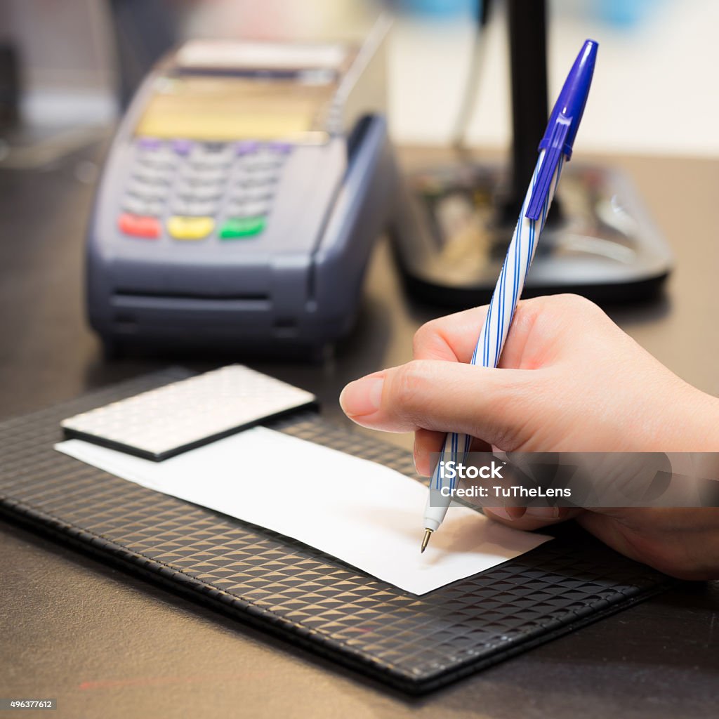 Consumer signing on a sale transaction receipt with Credit Card Consumer signing on a sale transaction receipt with Credit Card Machine and Barcode Scanner in Background 2015 Stock Photo