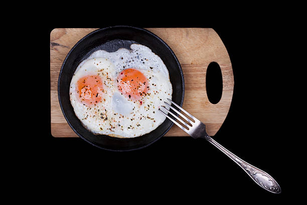 istock Scrambled eggs in iron skillet, top view isolated black 496380850