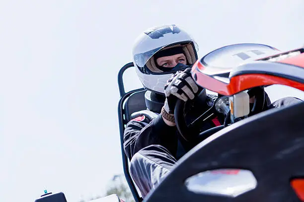 view from below of a concentrated gokart pilot on the starting line before starting a race in an outdoor go karting circuit - focus on the right eye