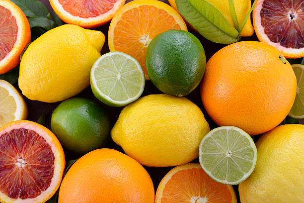 Orange, Lemon and Lime Citrus Fruit Mixed citrus fruit including navel and blood oranges, lemons and limes on dark wood table. navel orange photos stock pictures, royalty-free photos & images