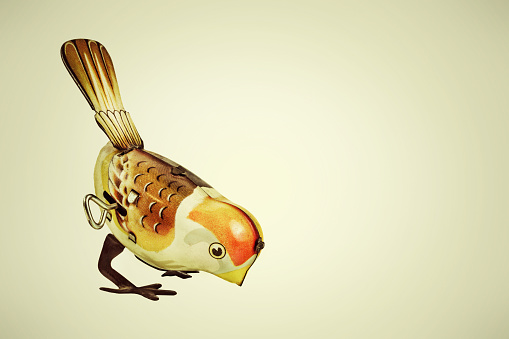 Retro styled image of a tin wind up toy bird on a vintage background