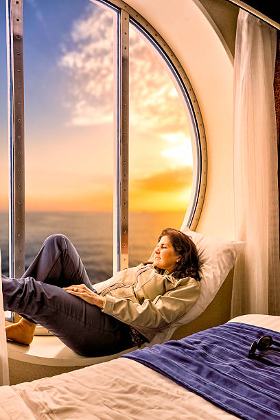 Hispanic woman relaxing on yacht cabin window at sunset
