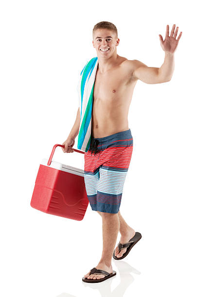 счастливый молодой человек, ходить с прохладу и размахивающий лапами - male swimwear cooler 20s стоковые фото и изображения