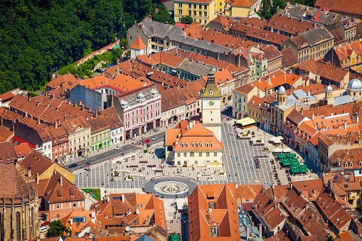 High Angle view of the town of Brasov in Romania centered on the Town Hall building. People can be seen going about their activities in the town square.
