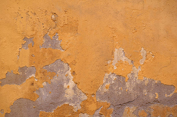 istock Texture of old wall covered with yellow stucco 496410122