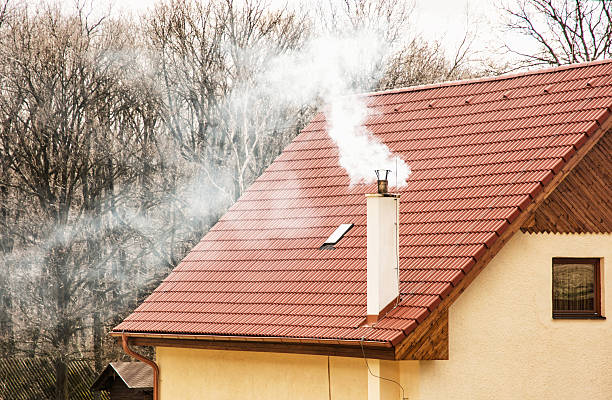 Red roof and smoking chimney stock photo