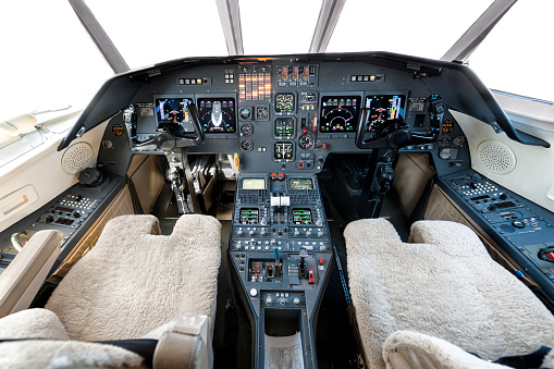 Cuneo, Italy - October 7, 2015:  This photo was captured in airport runway in Italy during day. We can see detail of cockpit of an airline in daylight. Instruments, screens, gauges, and flight controls are standing out against the dark blue and grey background panel.