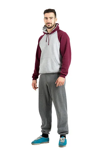 Young bearded male in sport casual clothes smiling looking at camera. Full body length portrait isolated over white studio background.