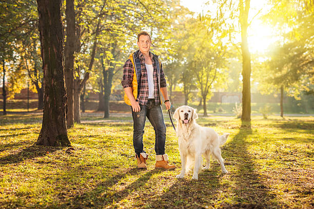 istock Man standing in a meadow and posing with a dog 496412798