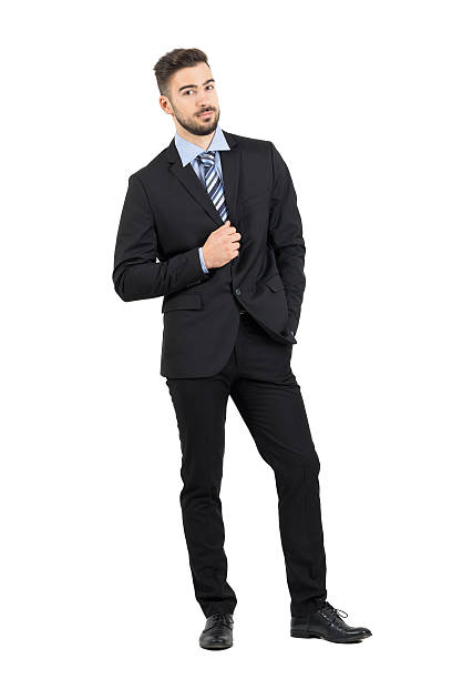 istock Bearded young businessman in suit holding collar looking at camera 496412800