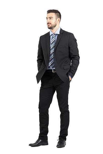 Businessman in suit with hands in pockets smiling looking away Businessman in suit with hands in pockets smiling and looking away. Full body length portrait isolated over white studio background. hands in pockets stock pictures, royalty-free photos & images