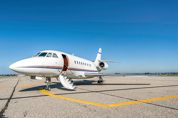 Ready private jet Close-up and side view of white luxury private jet with red and blue stripe on airport runway ready for passenger boarding. flight of steps stock pictures, royalty-free photos & images