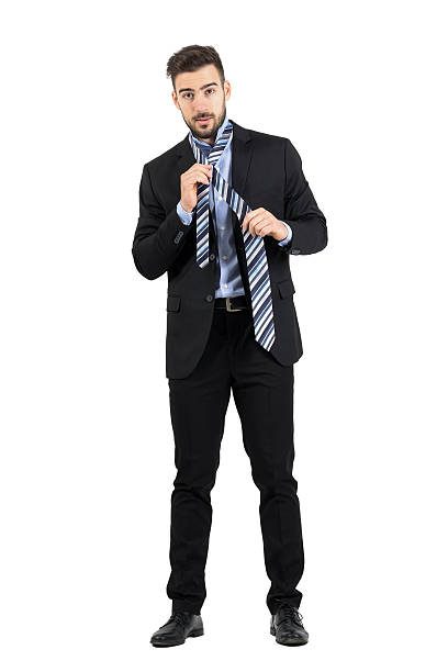 istock Bearded young corporate man tying necktie looking at camera. 496413906