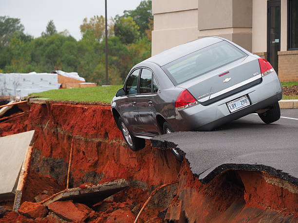 Car Teeters on the Edge of Meridian Mississippi Sink Hole Meridian, Mississippi, USA - November 9, 2015: A huge sinkhole opens up next to a new I Hop restaurant in Meridian Mississippi. sinkhole stock pictures, royalty-free photos & images