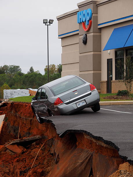 Sinkhole and Teetering Car at the Meridian Mississippi IHop Restaurant Meridian, Mississippi, USA - November 9, 2015: A huge sinkhole opens up next to a new I Hop restaurant in Meridian Mississippi swallowing cars and trucks. Ihop stock pictures, royalty-free photos & images