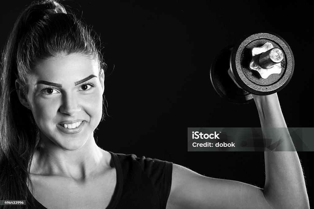 portrait abaout a beautiful fitness woman, black and white fitness woman lifting dumbbells isolated on black background, black and white photography 2015 Stock Photo