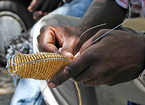 man making gifts to sell from beads