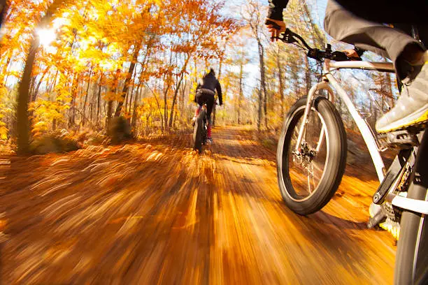 Couple riding fatbikes on trails in the fall