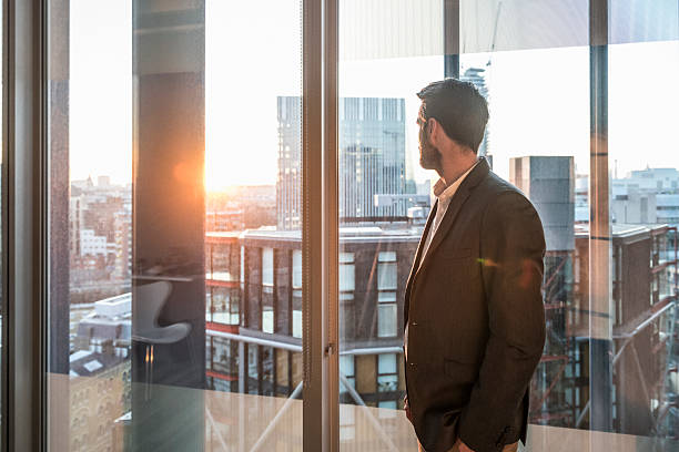 istock Businessman looking through office window in sunlight 496440844