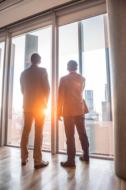 istock Businessmen looking out of modern office window 496441110