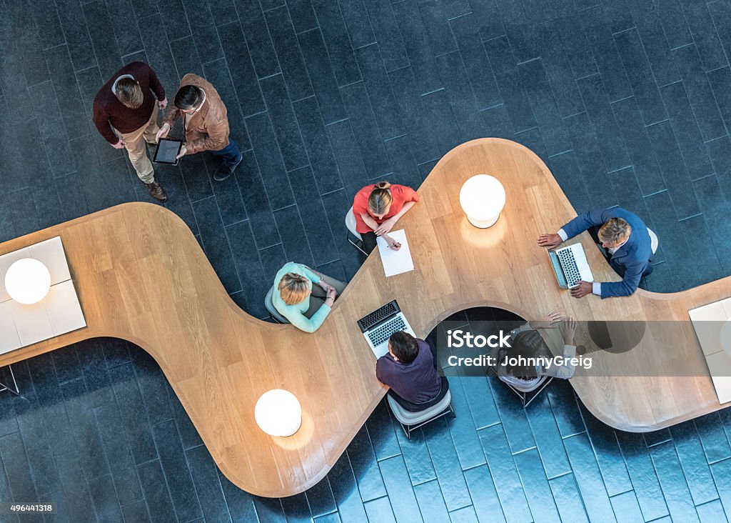 Business people meeting in modern office, view from above Office workers sitting at curved desk in business meeting. Professionals working using laptops. High Angle View Stock Photo