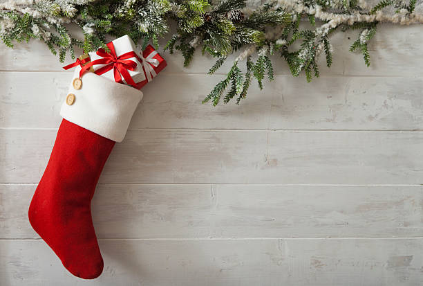 Christmas Stocking Christmas Stocking with gifts and bow hung on barn board with evergreen garland. Copy space. tree crown stock pictures, royalty-free photos & images