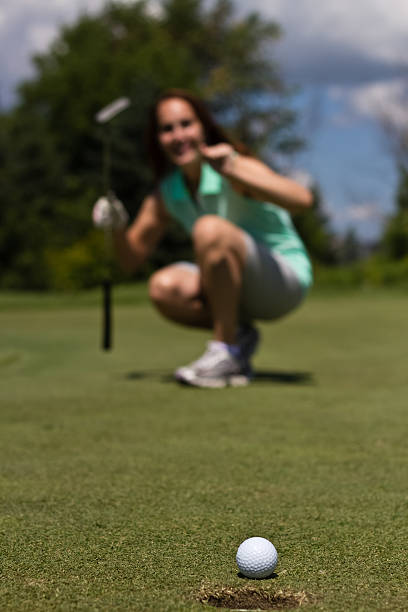 istock Woman putting golf ball into the cup 496443909