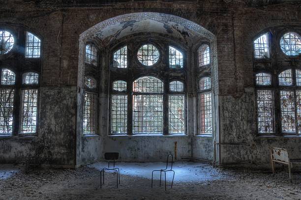 Old abandoned sanatorium in Beelitz Two chairs and a bed in a room with large windows beelitz stock pictures, royalty-free photos & images