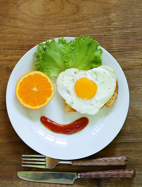 istock funny face serving breakfast, fried egg, toast and green salad 496444483