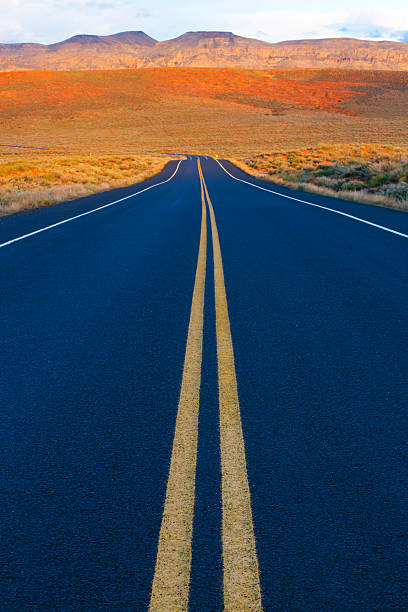 Middle Of The Road A quiet stretch of highway in Utah, USA. Popular with road bicyclists, motorcycle riders and motorists. single yellow line sunlight usa utah stock pictures, royalty-free photos & images