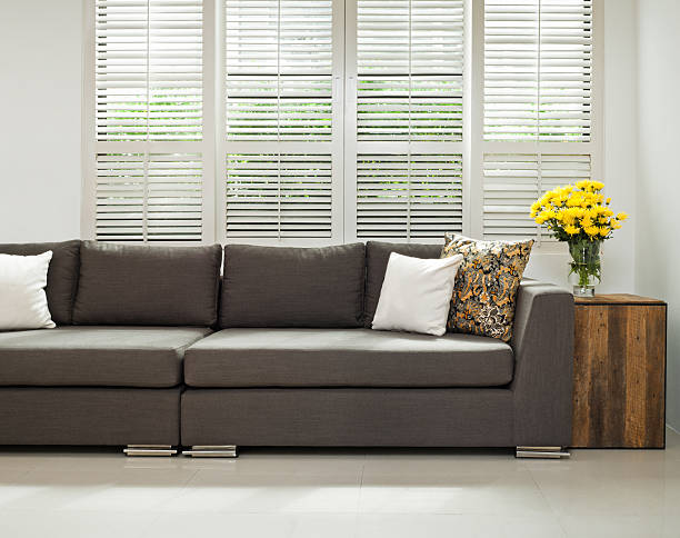 Grey sofa in simple setting Grey sofa with pillows infront of lovered windows shutter stock pictures, royalty-free photos & images