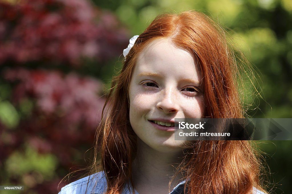 Pretty, happy girl with long red hair, smiling to herself Photo showing a pretty, happy girl with long red hair, pictured smiling to herself in the sunshine outside, as she relaxes in the garden on a sunny summer's afternoon. Beautiful People Stock Photo