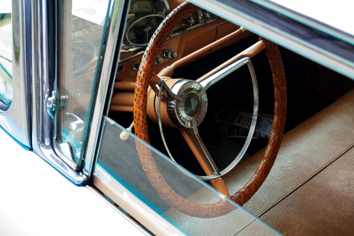 Essen, Germany - June 1, 2014: View and shot of leathern steering wheel of old US car and oldtimer through open window. Car is standing on grounds of Zeche Zollverein and shown on public and entrance free meeting fir showing private cars or offering.