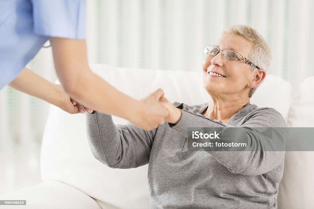 Un anziano donna di essere aiutato da un infermiere - Foto stock royalty-free di Accudire