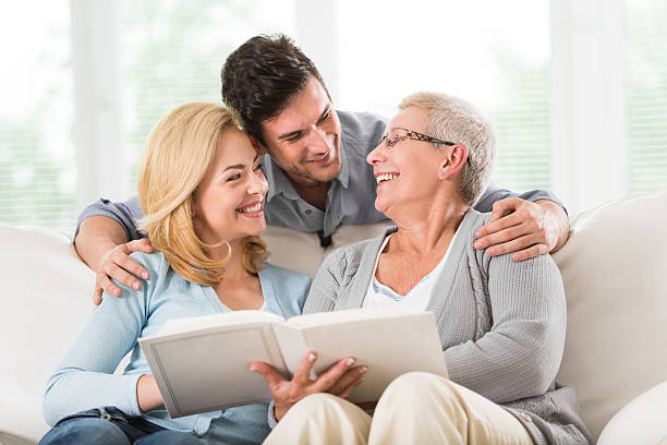 famiglia guardando le immagini in album - grandparent senior adult child reading foto e immagini stock