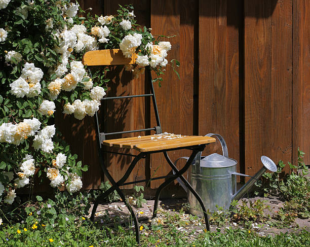 A serene garden setting with turquoise metal furniture surrounded by vibrant greenery and delicate blooms. The tranquil ambiance is complemented by the freshness of nature and hints of earthy aromas.