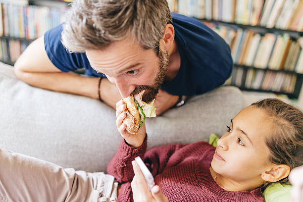 daughter feeding father with sandwich